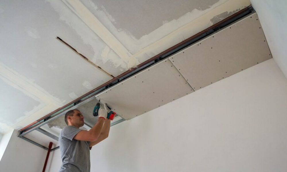 trabajador-construccion-ensambla-techo-suspendido-paneles-yeso-fija-panel-yeso-al-marco-metal-techo-destornillador_127089-4911